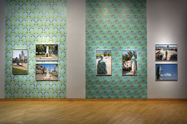 Joiri Minaya, The Cloaking of the statues of Ponce de Leon at the Torch of Friendship and Christopher Columbus behind the Bayfront Park Amphitheatre in Miami, Florida, 2019. archival pigment prints presented on custom wallpaper patterns. Courtesy of the artist. Photographs within the installation: The Cloaking of the statue of Christopher Columbus behind the Bayfront Park Amphitheatre, Miami, Florida; The Cloaking of the statue of Ponce de Leon at the Torch of Friendship on Biscayne Blvd, Miami, Florida, dye-sublimation print on spandex fabric and wood scructure. Photos by Zachary Balber, commissioned by Fringe Projects Miami. Courtesy of the artist. Photo: Will Lytch.