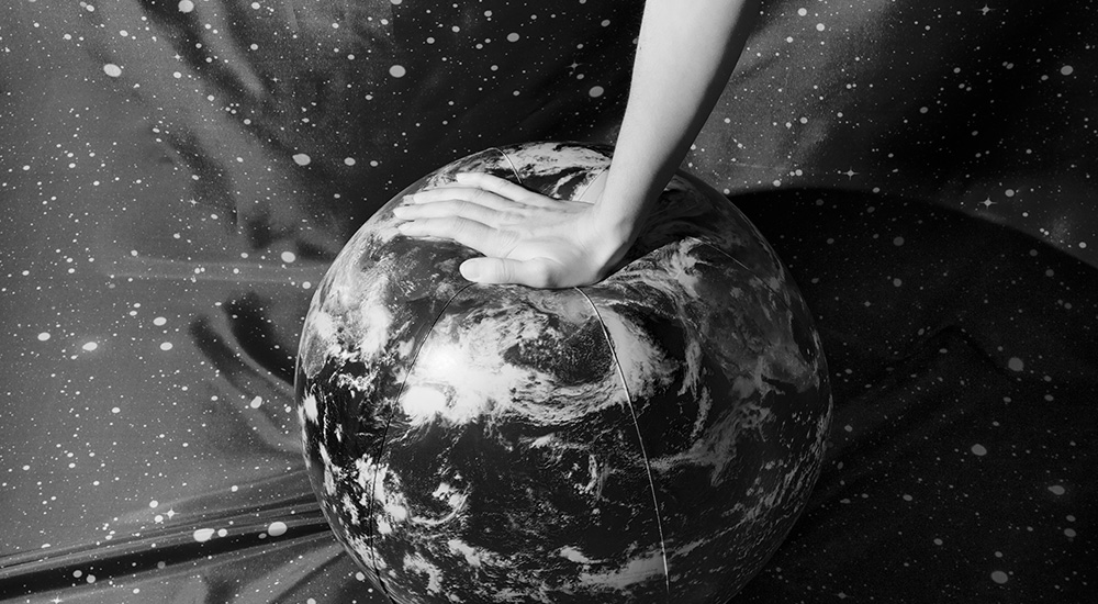 Image: Diana Sosnowska. an arm and hand pushing down on an inflatable earth